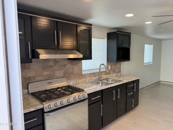 a kitchen with stainless steel appliances granite countertop a sink and a stove top oven with wooden floor