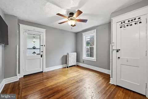 an empty room with wooden floor chandelier fan and windows