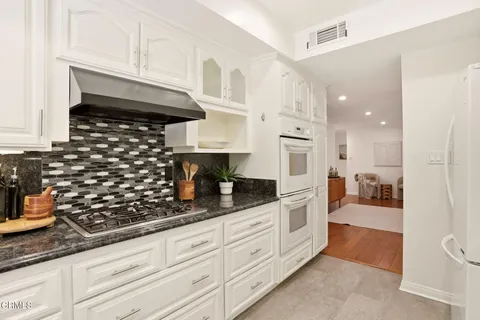a kitchen with white cabinets and appliances