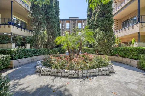 a view of a multi story residential apartment building with a yard and potted plants