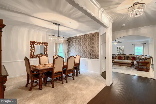 a living room with stainless steel appliances granite countertop furniture a rug a fireplace and a chandelier