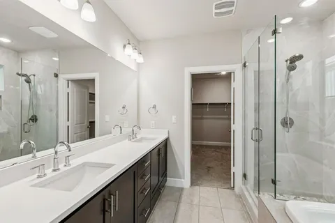a bathroom with a double vanity sink mirror and shower