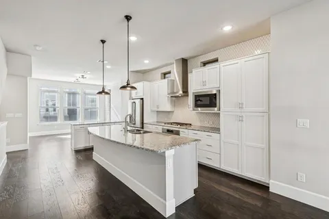 a large kitchen with kitchen island a stove a refrigerator a sink and wooden floor