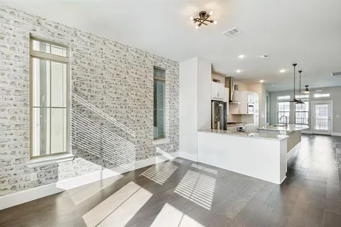 a view of a kitchen with kitchen island a sink wooden floor and a large window
