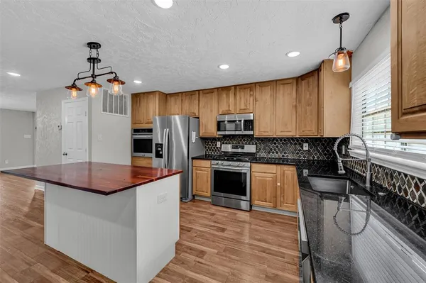 a kitchen with stainless steel appliances kitchen island granite countertop a stove a sink and a refrigerator