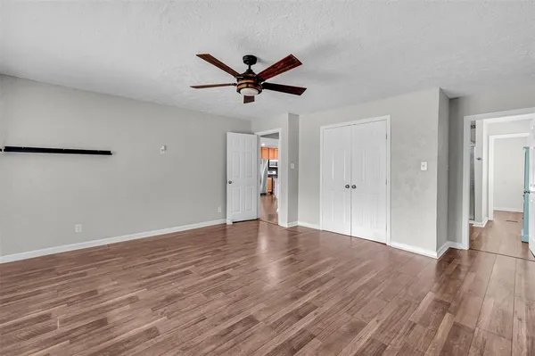 a view of empty room with wooden floor and ceiling fan