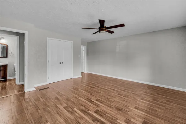 a view of a room with wooden floor and a ceiling fan