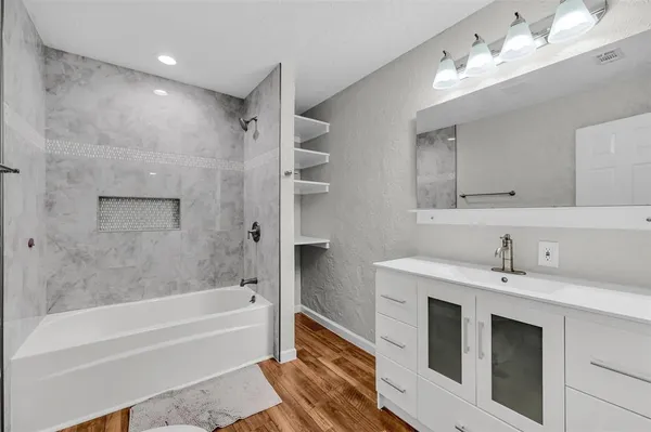 a bathroom with a tub sink double vanity and tub