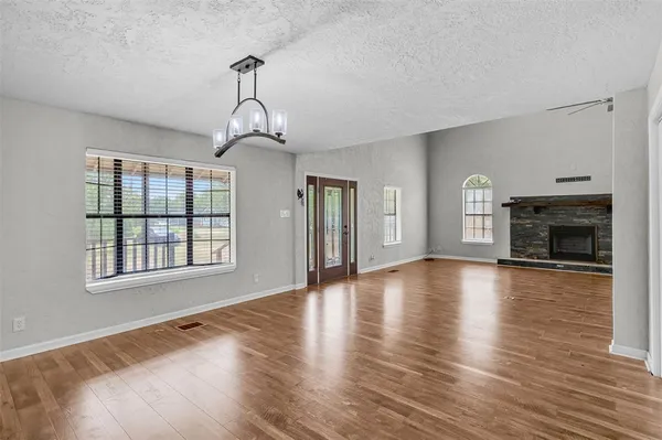a view of an empty room with window and wooden floor