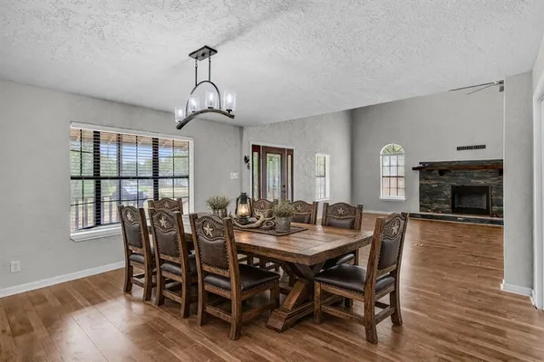 a dining room with wooden floor a chandelier a wooden table and chairs