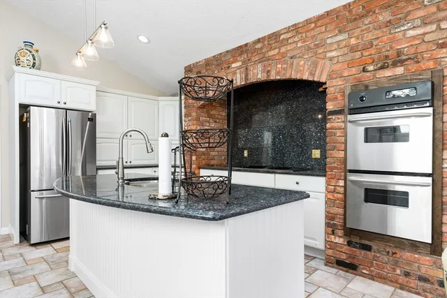 a kitchen with kitchen island a counter top space cabinets and stainless steel appliances