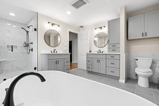 a spacious bathroom with a double vanity sink mirror and a toilet
