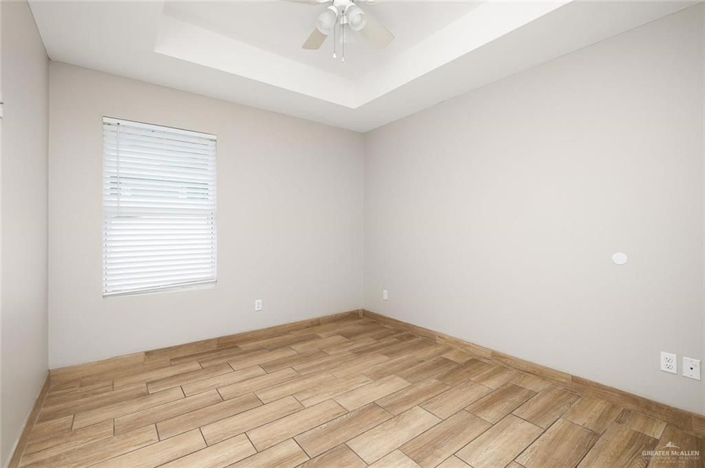 826 South Missouri Street, Unit C Alton, TX 78573 - Photo 7 of 9 Spare room with a tray ceiling, light wood-style flooring, and a ceiling fan