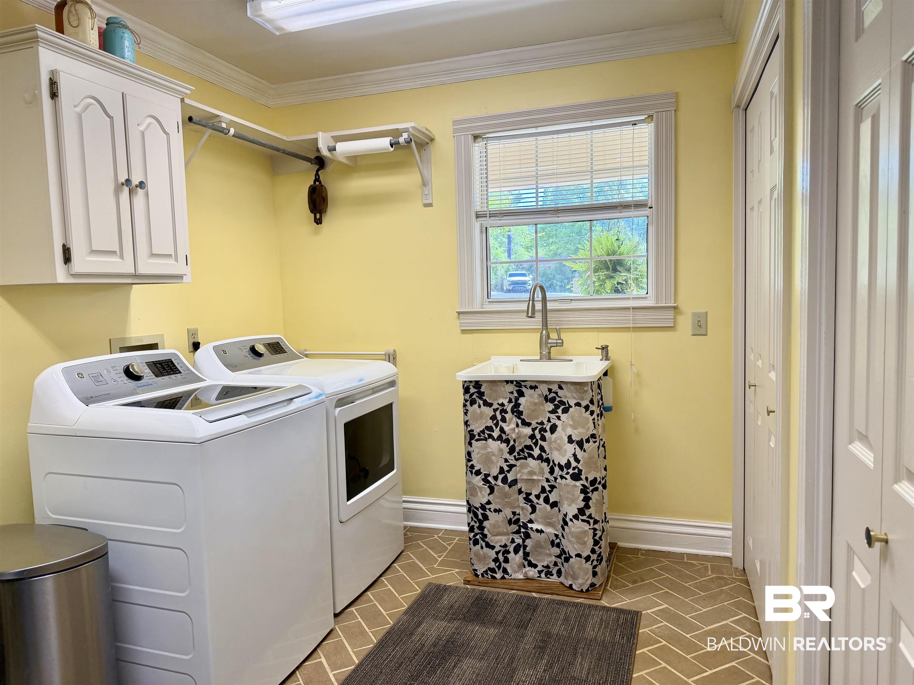 2944 Appleton Road Brewton, AL 36426 - Photo 31 of 65 Laundry area with washing machine and dryer, brick patterned floors, cabinet space, and crown molding
