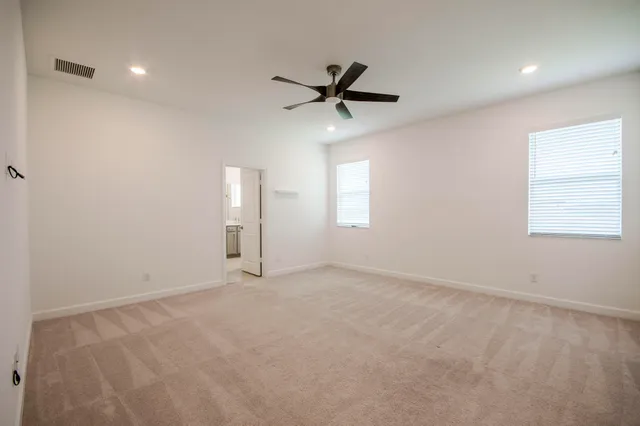 an empty room with windows and fan