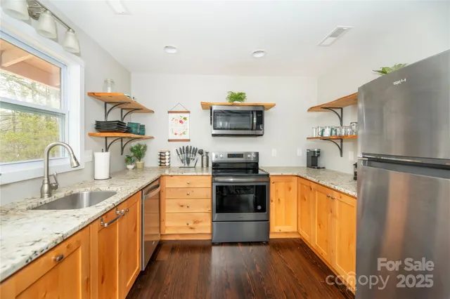 a kitchen with stainless steel appliances granite countertop a refrigerator a stove top oven a sink and dishwasher with wooden floor