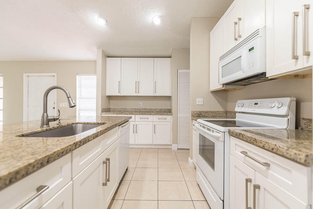 10225 Sleepy Brook Way Boca Raton, FL 33428 - Photo 11 of 41 a kitchen with granite countertop white cabinets and white appliances