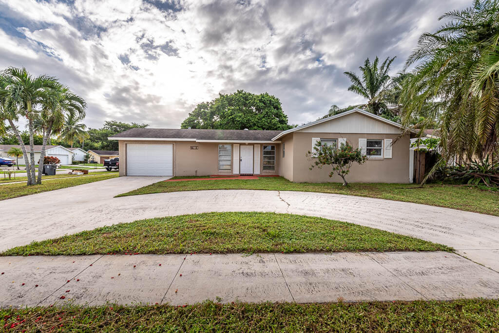 10225 Sleepy Brook Way Boca Raton, FL 33428 - Photo 2 of 41 a front view of a house with a garden and trees