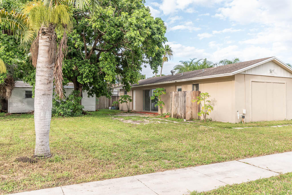 10225 Sleepy Brook Way Boca Raton, FL 33428 - Photo 9 of 41 a front view of a house with a garden and trees