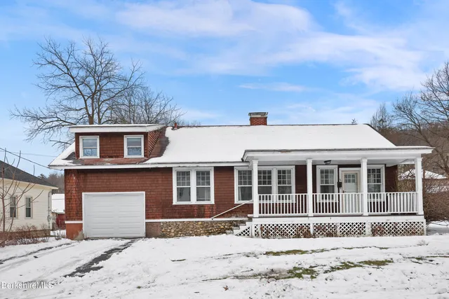 a front view of a house with a yard covered in snow