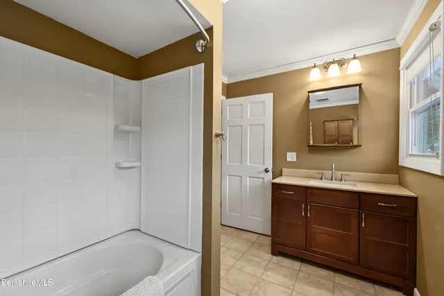 a bathroom with a tub a sink and mirror