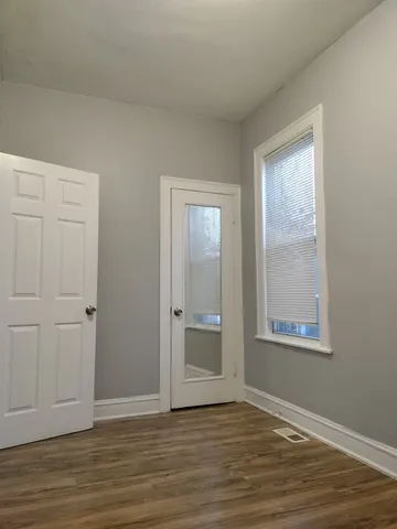 a view of an empty room with wooden floor and window