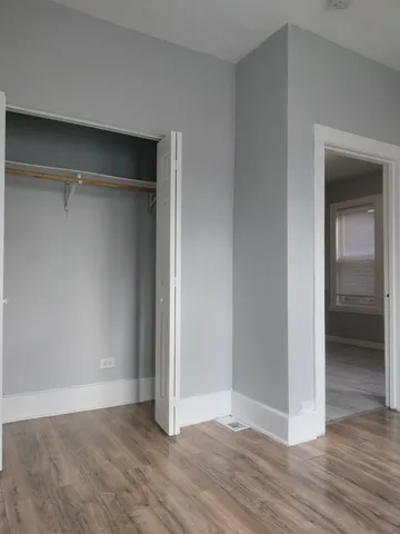 a view of an empty room with wooden floor & closet