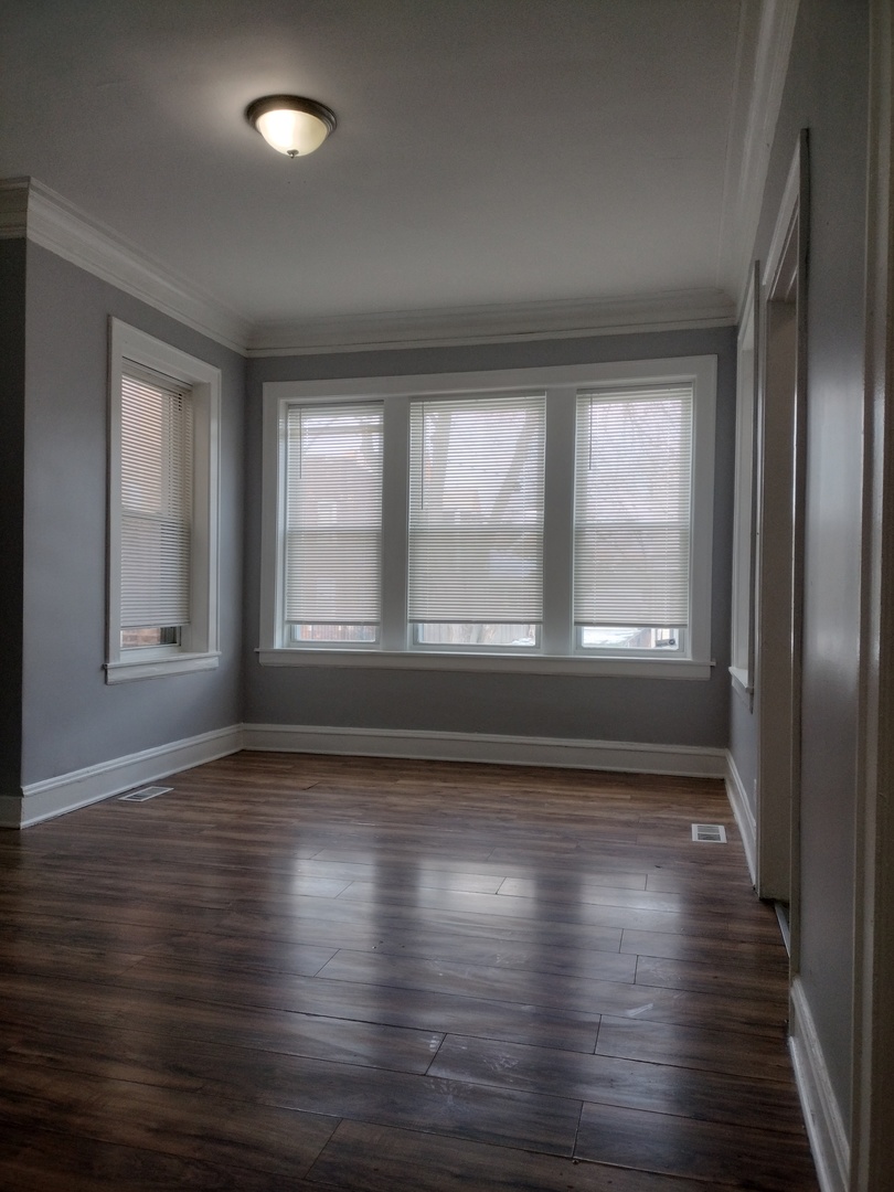 705 East 92nd Street Chicago, IL 60619 - Photo 5 of 23 an empty room with wooden floor and windows
