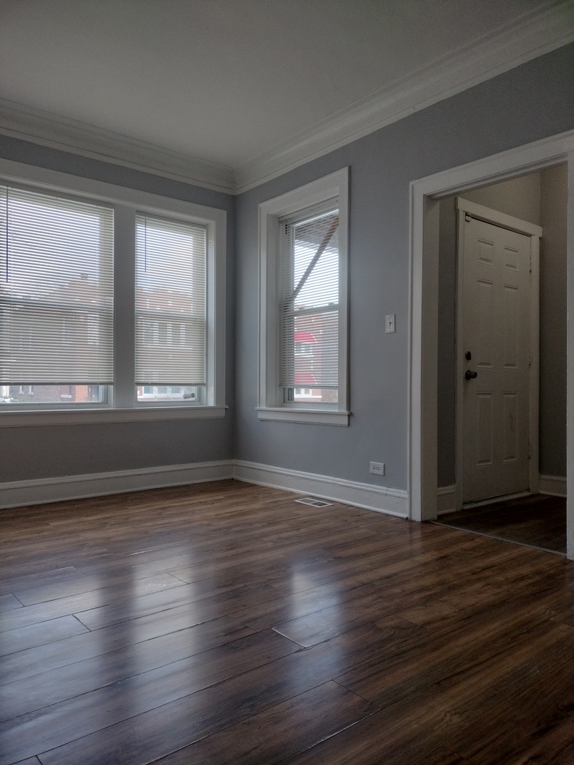 705 East 92nd Street Chicago, IL 60619 - Photo 6 of 23 a view of an empty room with wooden floor and a window