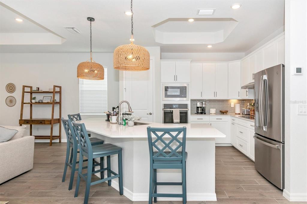 17672 Santorini Court Venice, FL 34293 - Photo 11 of 94 a kitchen with stainless steel appliances kitchen island granite countertop a refrigerator a stove a kitchen island with a dining table and chairs
