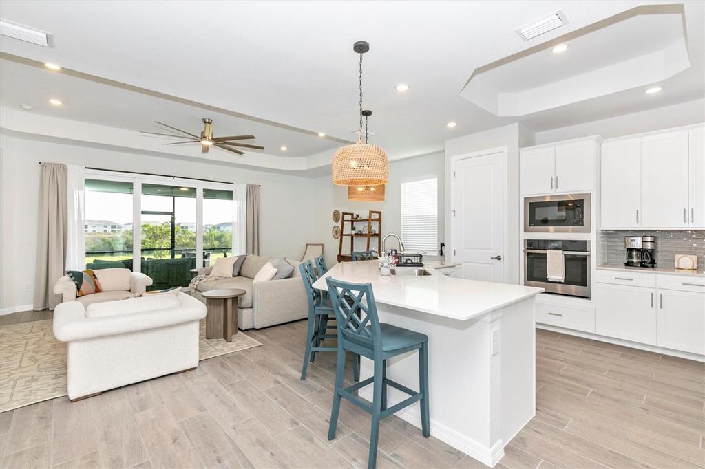 17672 Santorini Court Venice, FL 34293 - Photo 14 of 94 a large kitchen with kitchen island a large counter space a sink appliances and living room view