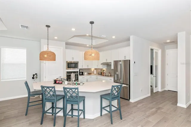 a large kitchen with kitchen island a large counter space a sink appliances and living room view