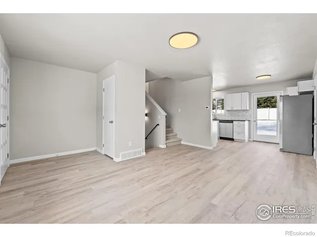 a view of an empty room with wooden floor and stairs