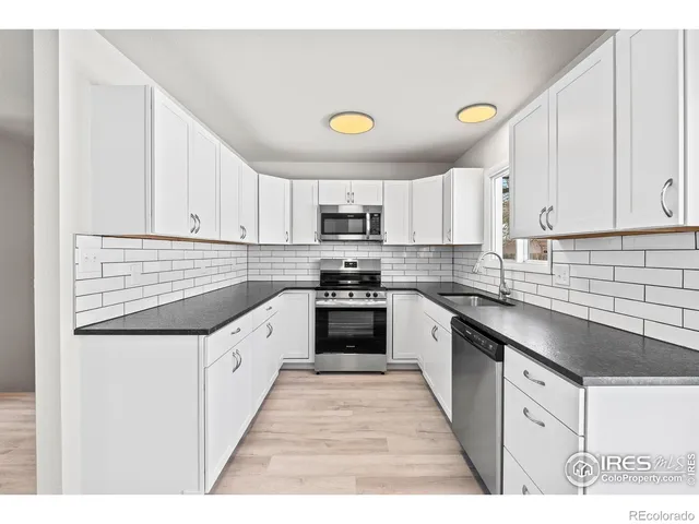 a kitchen with kitchen island granite countertop a stove top oven a sink a counter space and cabinets