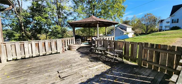a view of a wooden deck with chairs and large trees