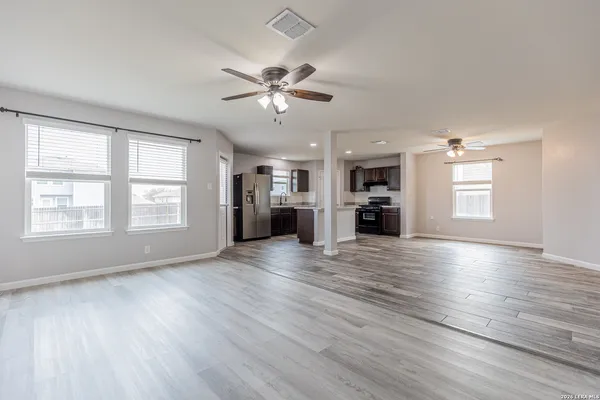 a view of an empty room with a window and wooden floor