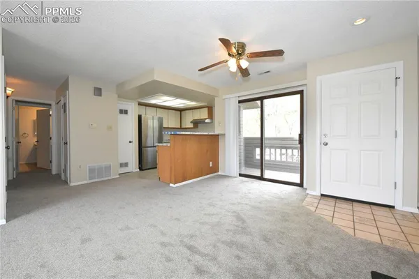 an empty room with chandelier fan and windows