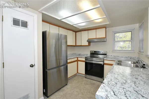 a kitchen with stainless steel appliances granite countertop a refrigerator sink and stove