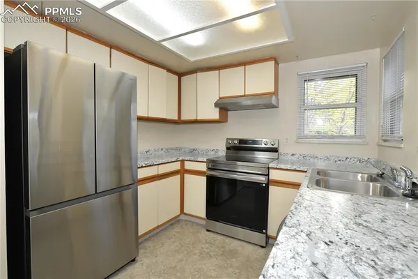 a kitchen with stainless steel appliances granite countertop a refrigerator a sink a stove and white cabinets