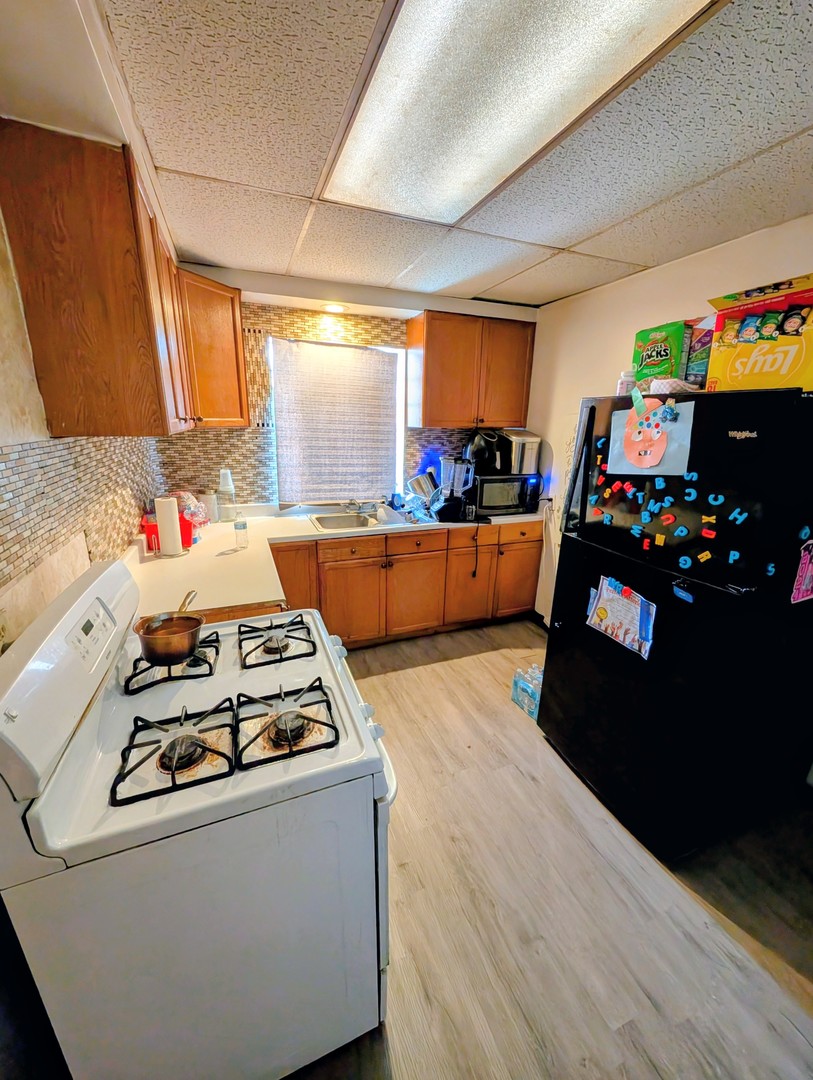 9035 South Bishop Street Chicago, IL 60620 - Photo 5 of 5 a kitchen with stainless steel appliances a stove a sink dishwasher and a refrigerator with wooden floor