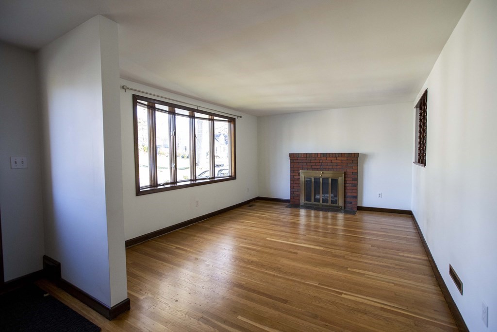 69 Sturges Road Reading, MA 01867 - Photo 3 of 42 an empty room with wooden floor fireplace and windows
