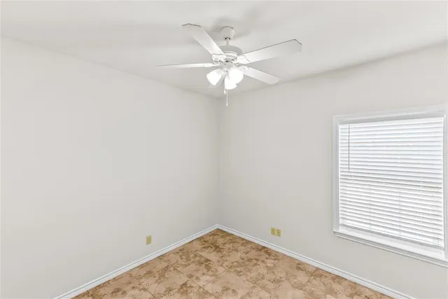 an empty room with a window and a fan