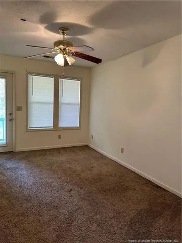 an empty room with a chandelier fan and windows