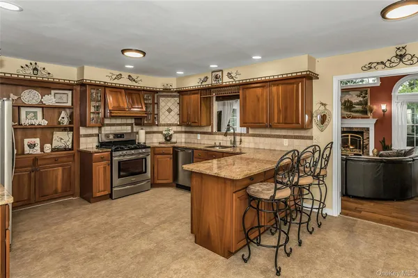 a kitchen with stainless steel appliances kitchen island granite countertop a stove top oven a sink a dining table and chairs