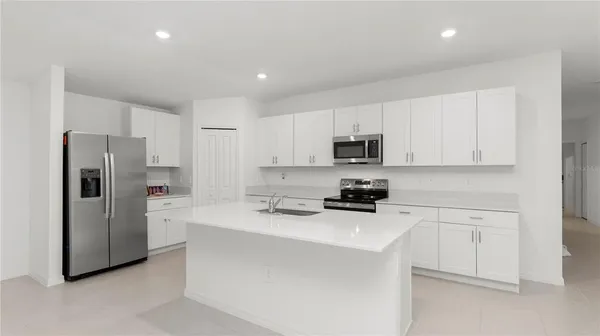 a kitchen with refrigerator a stove and white cabinets