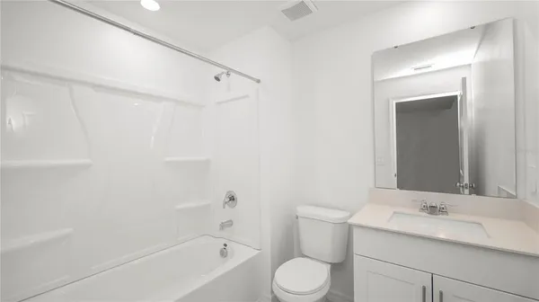 a bathroom with a toilet a sink a mirror a bathtub and vanity