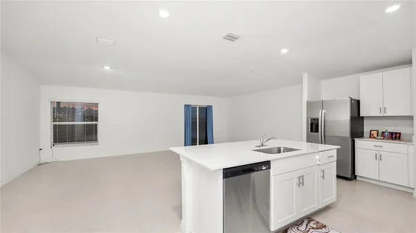 a kitchen that has a lot of white cabinets and stainless steel appliances