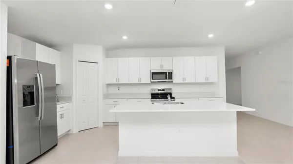 a kitchen with stainless steel appliances a refrigerator sink stove and white cabinets