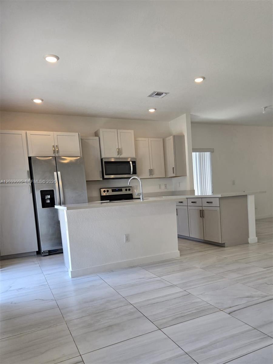 862 Southeast 17 Street, Unit 862 Homestead, FL 33034 - Photo 22 of 39 a large white kitchen with a stove a refrigerator and white cabinets