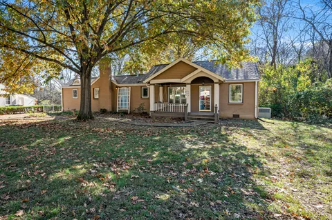 a front view of a house with a yard and large trees